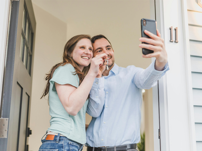 man and woman holding keys in front of a house door